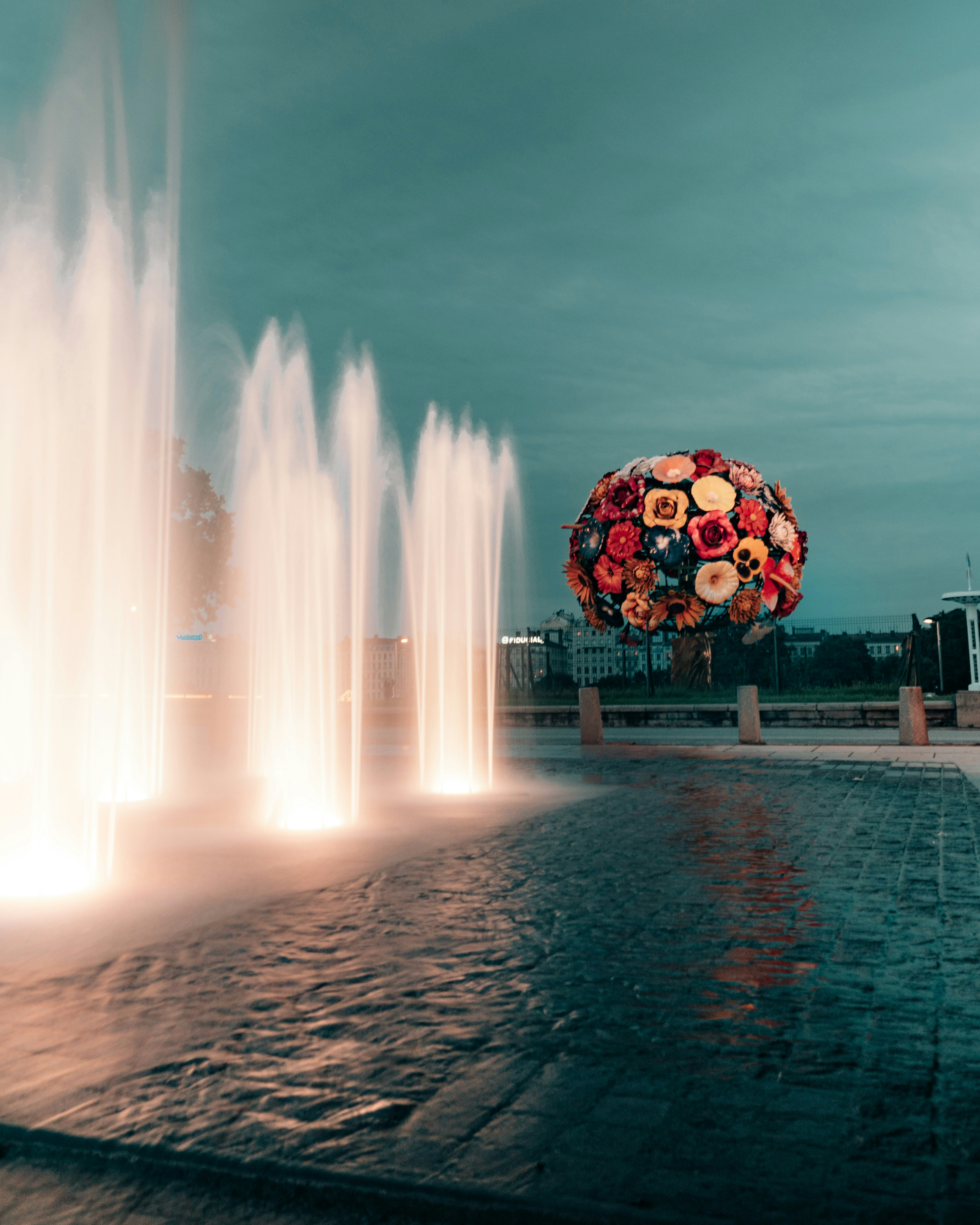 water fountain near brown wooden bench during night time